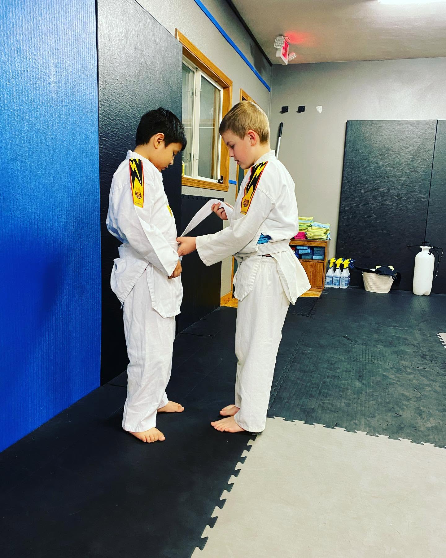 Coach helping a young student tie his belt at Fearless MMA